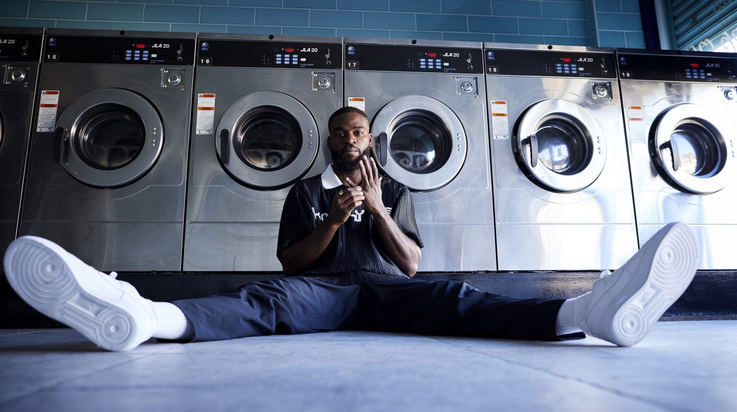 Joshua Buatsi sat on the floor with his legs out wide under some clothes washing machines