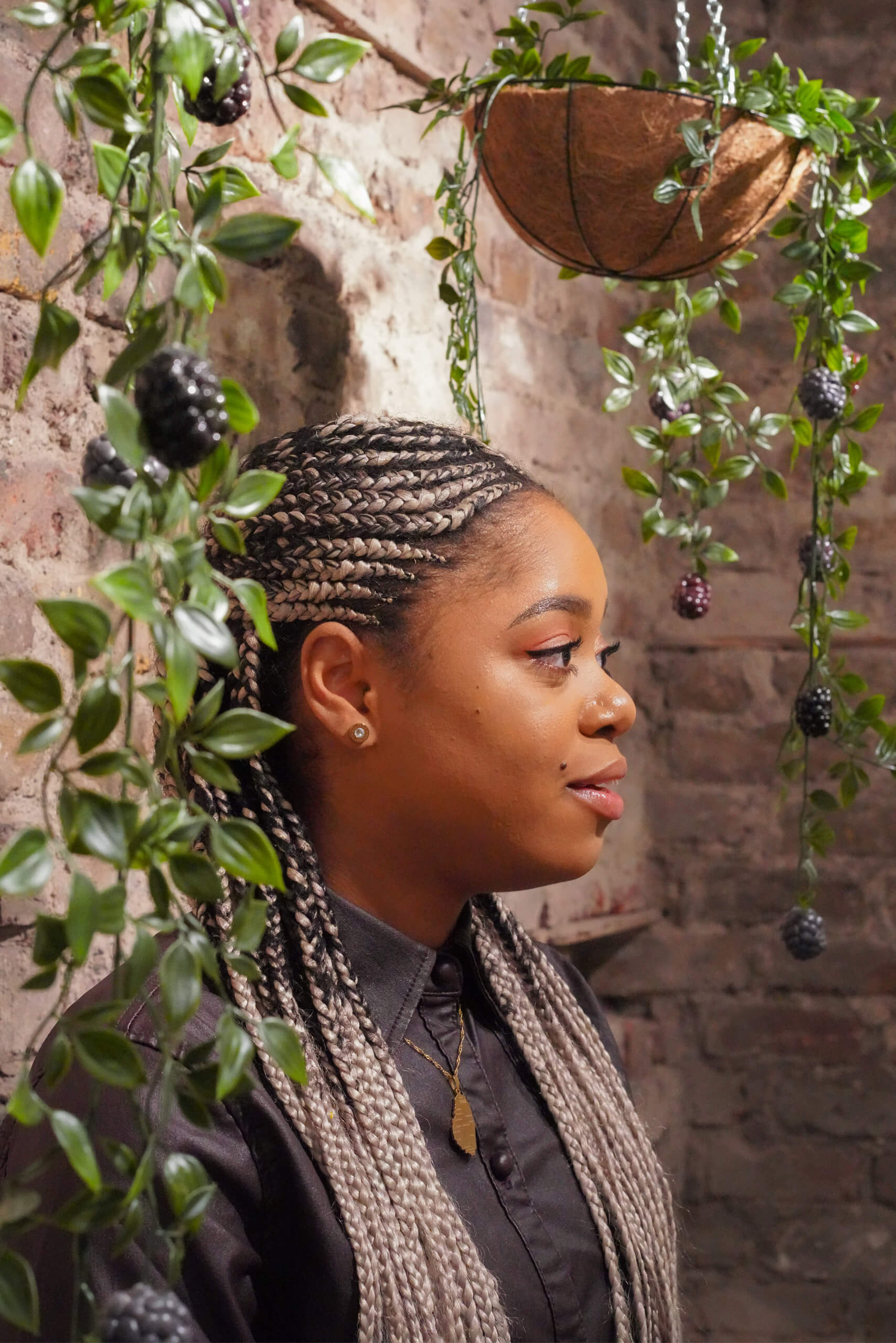 Lauren Marie Haywood under some of her handmade artwork mounted on a brick wall