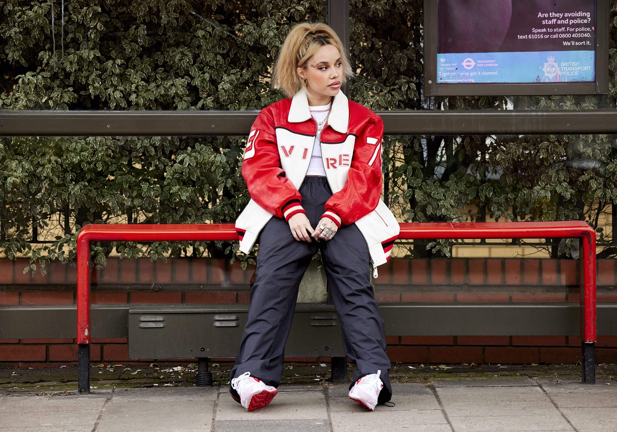 JGRREY sitting at a bus stop on a red bench