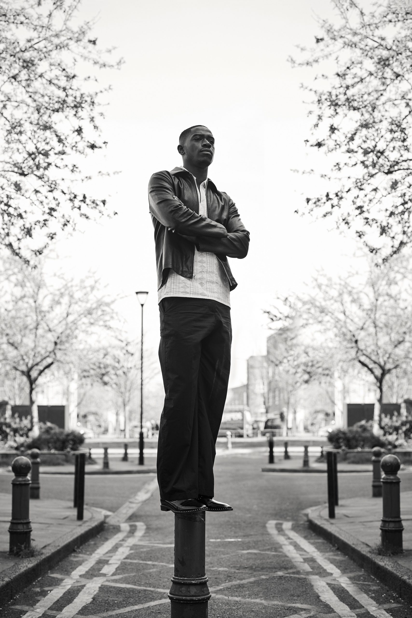 Damson Idris stood on a bollard with his arms crossed