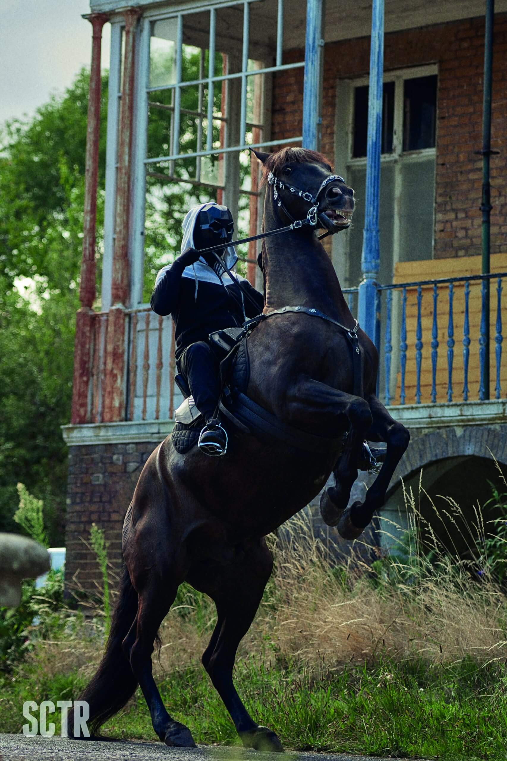 A hooded figure riding a rearing horse